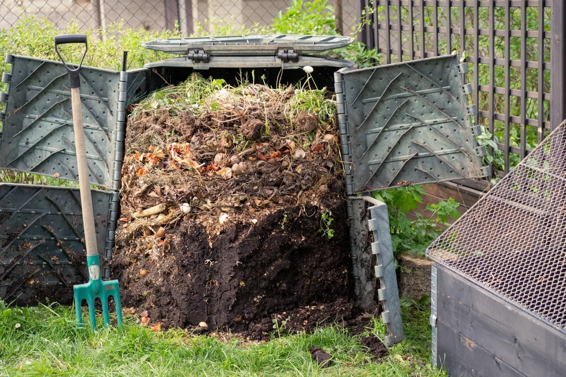 Offener Komposter mit Gartenabfällen und Gabel